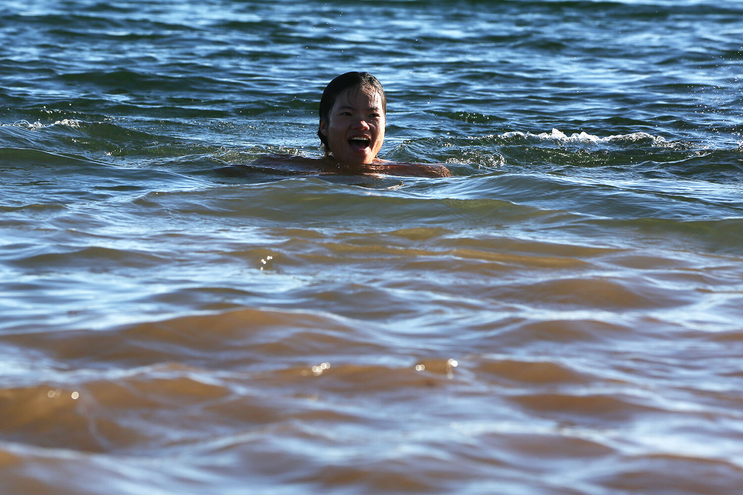 Saya Sheffield laughs as she floats near the beach